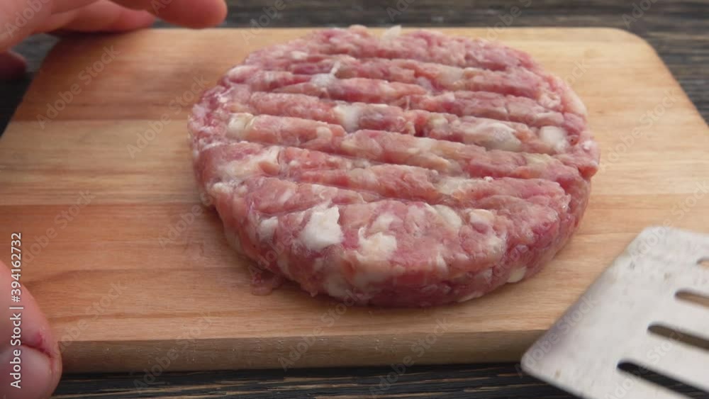 Close-up of the raw meat burger cutlet with onions taken from the wooden board with a spatula Close-up of the raw meat burger cutlet with onions taken from the wooden board with a spatula