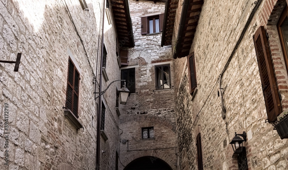 A narrow alley of an italian  medieval village with stone buildings, wooden roofs and windows (Gubbio, Italy, Europe)