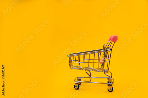 Empty shopping cart on yellow background with empty space for text. Shopping sale concept 