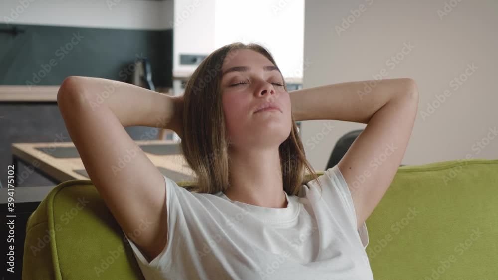 Calm young woman resting breathing fresh air feeling mental balance enjoying wellbeing at home on sofa in living room. Attractive female holding hands behind head relax on comfortable couch. Calm young woman resting breathing fresh air feeling mental balance enjoying wellbeing at home on sofa in living room. Attractive female holding hands behind head relax on comfortable couch.