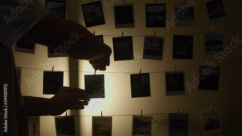 silhouette of asian man attach printed photo on rope string at glass wall decoration. home portfolio arts gallery displaying. all photos shot by Vajirawich Wongpuvarak.