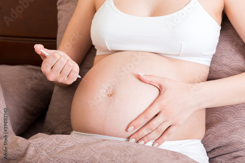 Pregnant woman with insulin syringe in home on bed. Pregnant diabetes concept