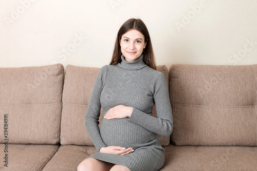 Pregnancy woman in beautiful dress sitting on the home