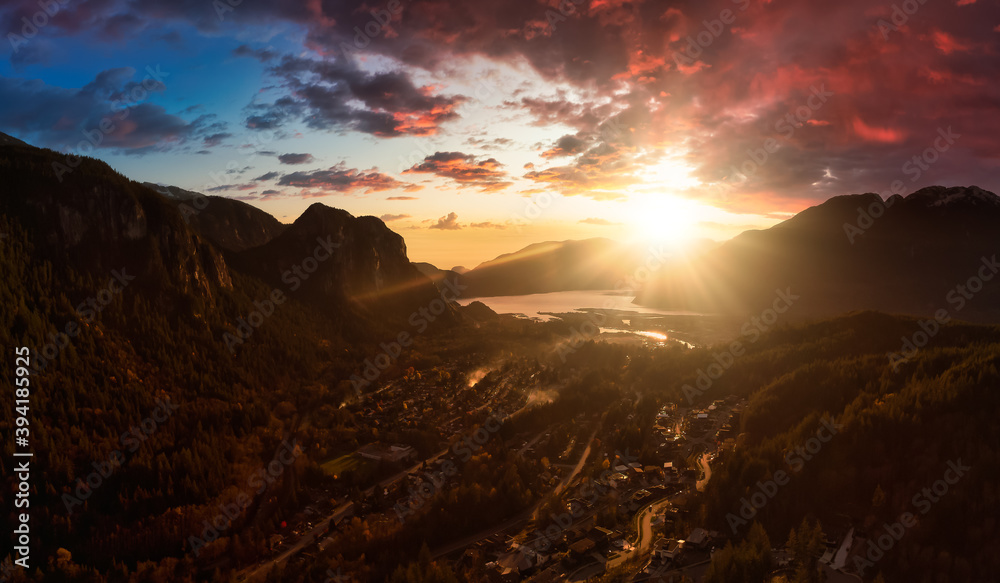 Squamish, North of Vancouver, British Columbia, Canada. Beautiful Aerial Panoramic View of a small town surrounded by Canadian Nature during Autumn Season. Dramatic Sunset Sky.
