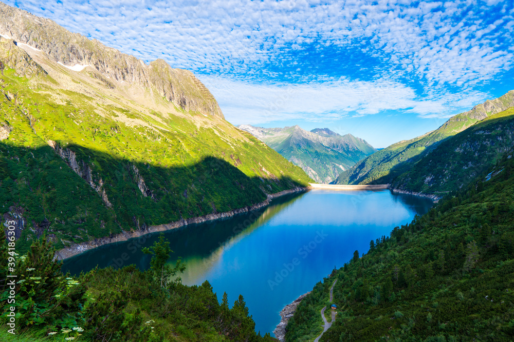 Morning mountain dawn in the Alps surrounded by summer green in the background high Alps, cloud sky. Reflections mountains in the water Zillergrundl austria zillertaler alps