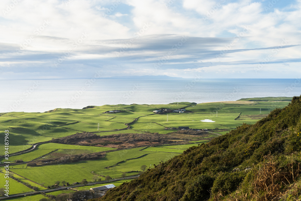 Looking over the green coast line around Gutterby and the Isle of Man beyond the Irish Sea, from the middle of Black Combe in the western Lake District National Park in England. Looking over the green coast line around Gutterby and the Isle of Man beyond the Irish Sea, from the middle of Black Combe in the western Lake District National Park in England.