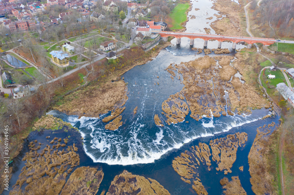 Aerial view of Venta Rapid (Ventas Rumba) waterfall. Widest waterfall in Europe and The Old Brick Bridge across the Venta river in Kuldiga
