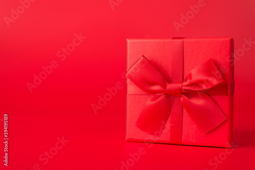 Surprise concept. Close up photo of red giftbox with red ribbon isolated on red background with copyspace