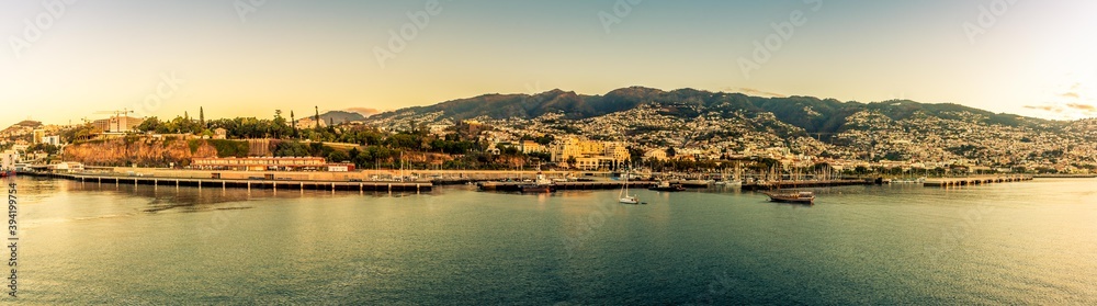 A panorama view across the port of Funchal, Madeira with the shore bathed in the glow of the early morning light