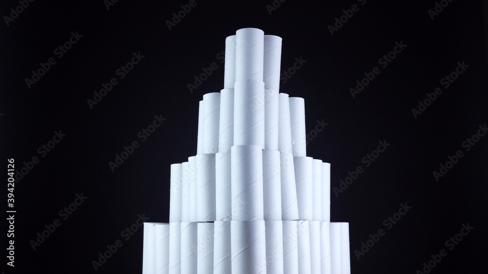 Obraz premium Empty toilet paper rolls on black background. Pyramid of hygiene items, empties toiletries exhausted during Covid-19 coronavirus epidemic lockdown. Empty stocks at quarantine and self-isolation.