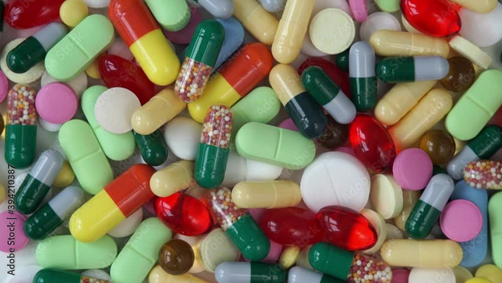 Top view of different colored medical pills rotate in circle. Pills and drugs. Pharmaceutical Industry. Medicine concept. Top view of different colored medical pills rotate in circle. Pills and drugs. Pharmaceutical Industry. Medicine concept.