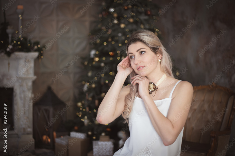 Beautiful young woman in the living room near the Christmas tree. Brooding or lonely, retro style.