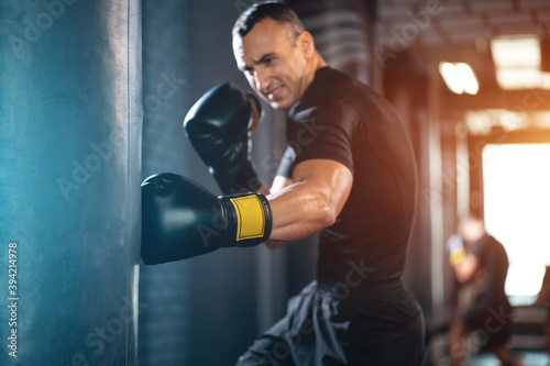 athletic sport man boxer training with punching bag or exercising in gym © goami