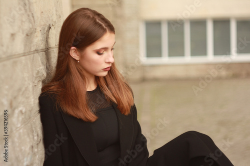 Beautiful young girl in a fashionable black dress and a long coat.