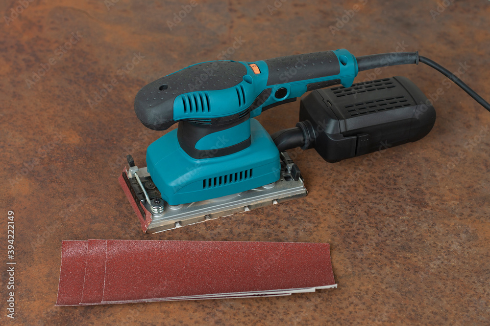 Electric sheet finishing sander and three abrasive papers on old rusty
