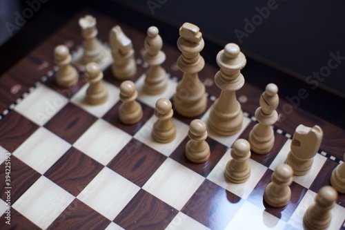 wooden white and black chess pieces on the board. blurry background.