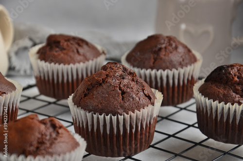 Chocolate muffins on a black metal grill on a gray background.