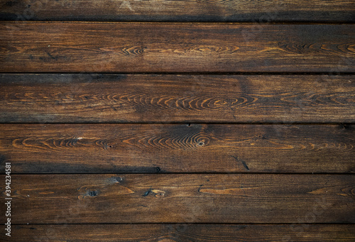 A background of dark wood planks tightly adjacent to each other. Wooden boards with a clearly visible wood texture.