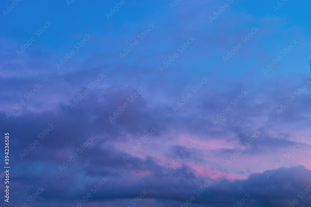 Background of mystery purple and pink clouds on blue sky at evening after sunset. Telephoto zoom photo shot