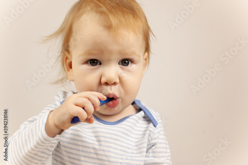 little baby practicing brushing teeth on his own. Kid with red hair brushes teeth. Oral hygiene.
