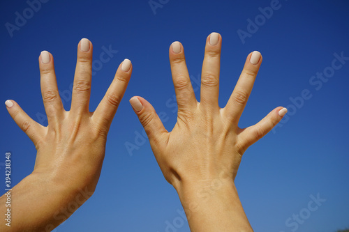 women's fingers on the clear blue sky show the number nine photo