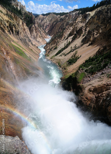 View To Mist Of The Yellowstone River From The Brink of Lower Falls Viewpoint On A Sunny Summer Day With A Clear Blue Sky And A Few Clouds