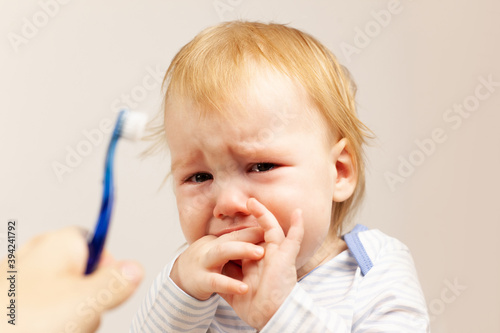 the kid does not want to brush his teeth and is unhappy. oral care. First teeth.