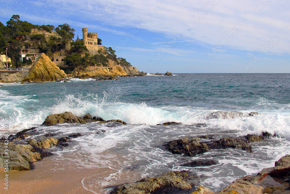 Castell d'en Plajan on the Costa Brava and city beach in Lloret de Mar, Spain. Sand and sea waves.