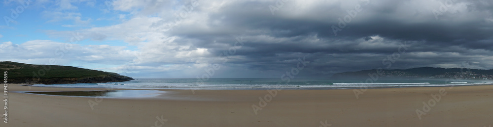 panorama of an empty and large beautiful golden sand beach underneath a bad weather sky panorama of an empty and large beautiful golden sand beach underneath a bad weather sky