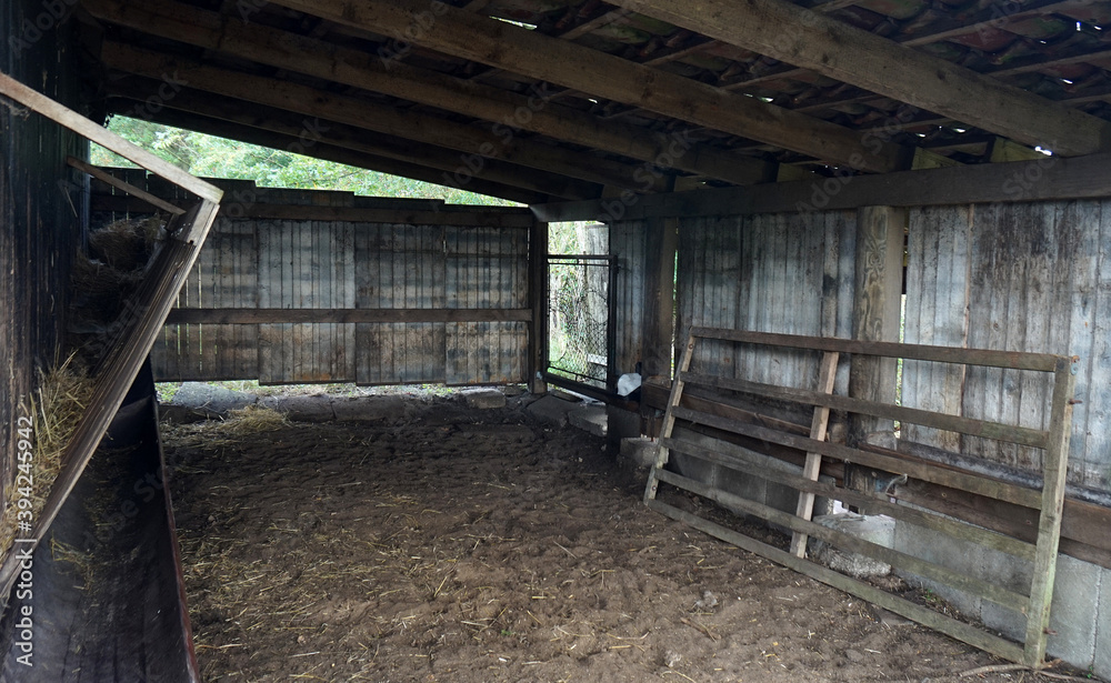 Outer part of a rustic old wooden sheepfold. Hay on the ground. The back is half open. Outer part of a rustic old wooden sheepfold. Hay on the ground. The back is half open.