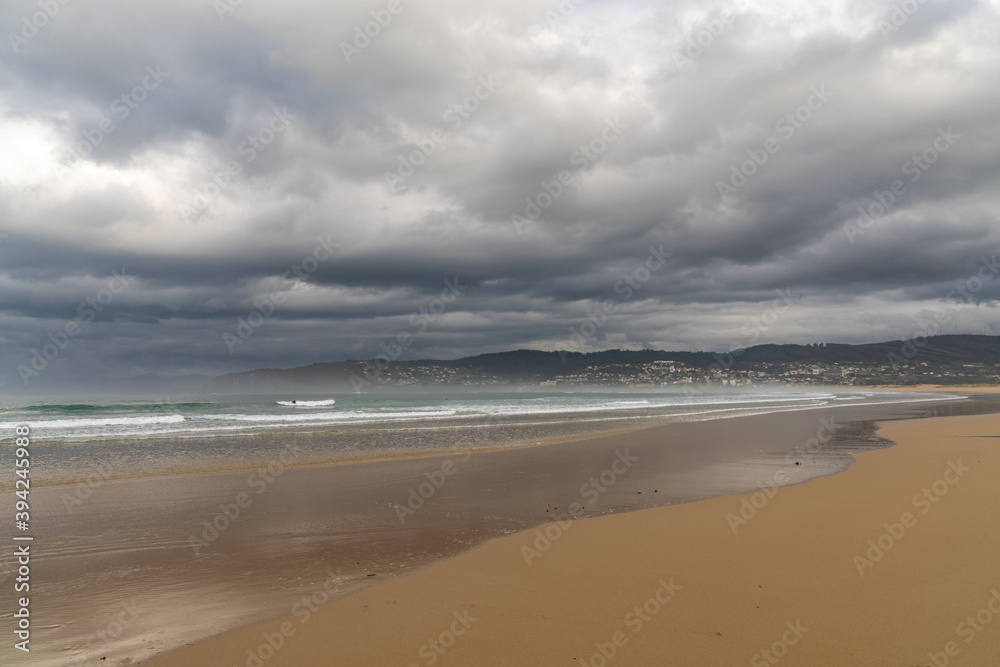 empty and large beautiful golden sand beach underneath a bad weather sky