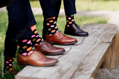 Feet of the groom and friends of the groom with funny colored socks. Men in colorful socks and black shoes. They stand in a circle. FASHION, STYLE, BEAUTY © Andriy Medvediuk