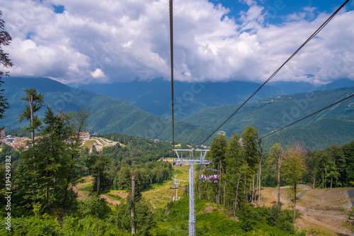 Ski lift in the mountains near the city of Sochi in summer. Scenic view with beautiful clouds over the Caucasus Mountains. Sunny day.