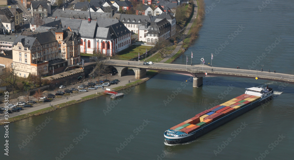 Inland cargo ship with colorful container freight passing a bridge in the historic old town of Bernkastel-Kues on the Mosel river in Germany