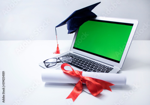 graduation cap and diploma with laptop, online education concept