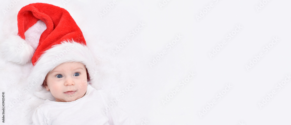 Christmas baby. Cute four month old baby in a Santa Christmas hat lying on back on white background. Copy space. Christmas and New Year Card. Christmas baby. Cute four month old baby in a Santa Christmas hat lying on back on white background. Copy space. Christmas and New Year Card.