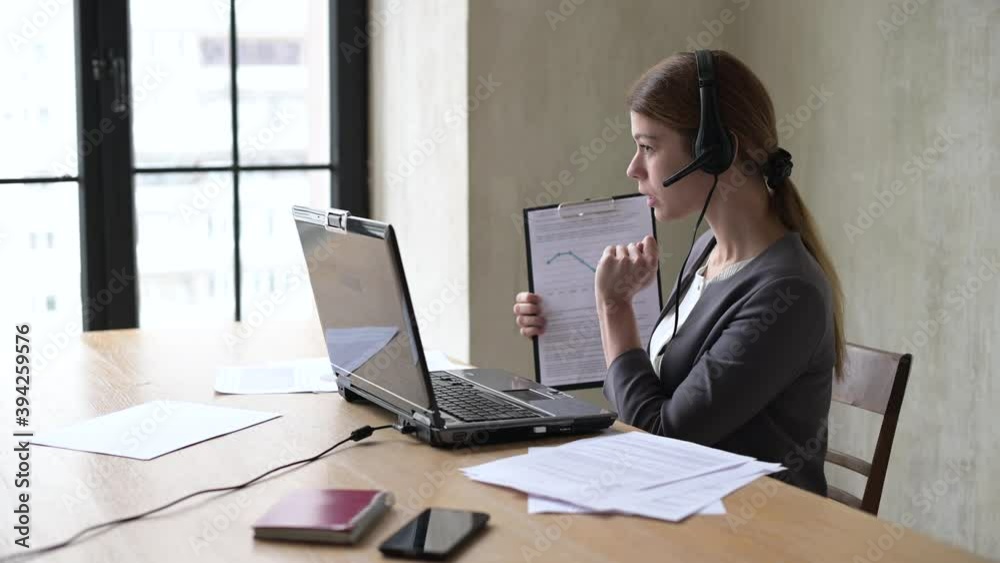 Young woman leads a remote meeting via laptop and shows graphs of growth and fall of profit Young woman leads a remote meeting via laptop and shows graphs of growth and fall of profit