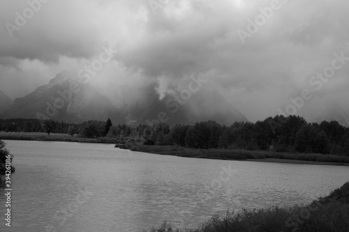 Mountain with clouds and a river in the foreground