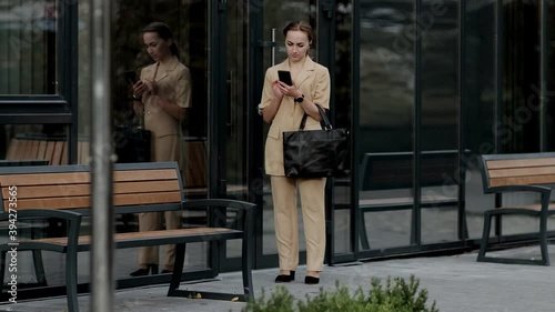 Adult Caucasian Confident Young Business Woman is Talking on Phone Outside near Modern Office Building