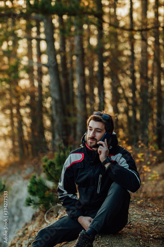 A young man uses a military compass for orientation in nature, talking on the phone, surrounded by fog.