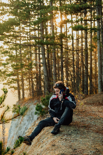 A young man uses a military compass for orientation in nature, talking on the phone, surrounded by fog.