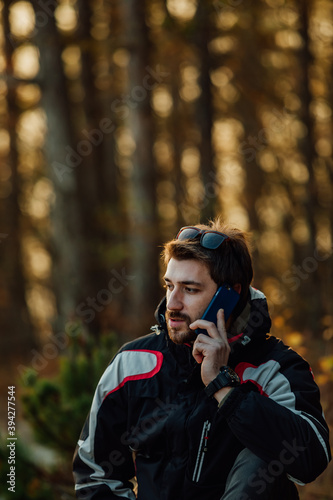 A young man uses a military compass for orientation in nature, talking on the phone, surrounded by fog.