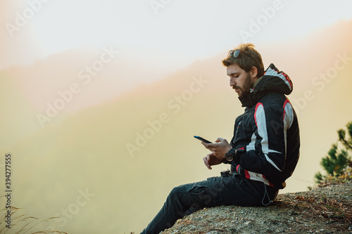 A young man uses a military compass for orientation in nature, talking on the phone, surrounded by fog.