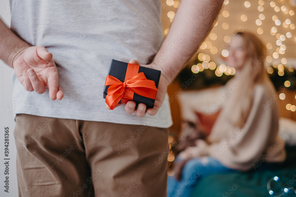Man crossed fingers hoping for good luck and holding gift box, preparing to make proposal for girlfriend, Christmas magic atmosphere Man crossed fingers hoping for good luck and holding gift box, preparing to make proposal for girlfriend, Christmas magic atmosphere