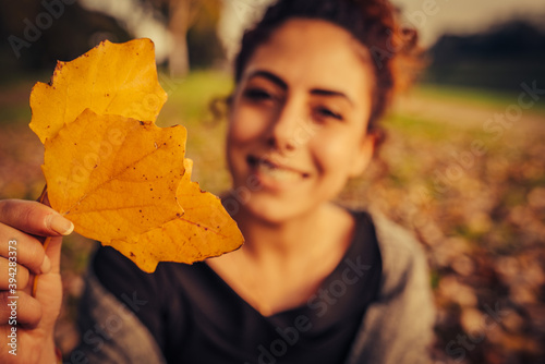 young woman playing having fun with the leaves in a park with autumn colors