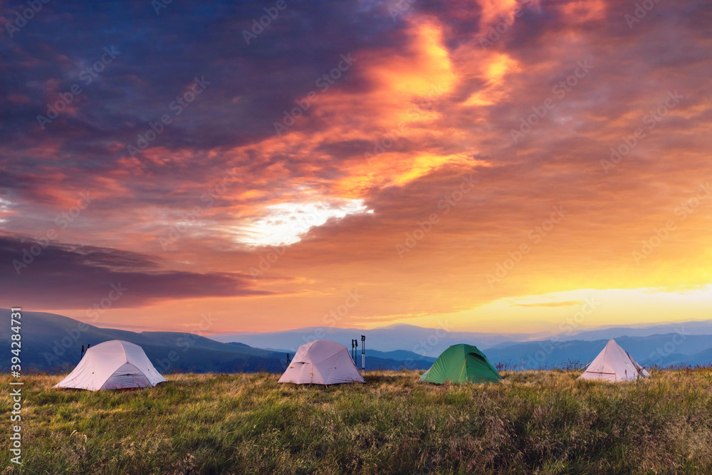 Four tents on amazing meadow in summer mountains. Tourists camp. Landscape photography, travel concept