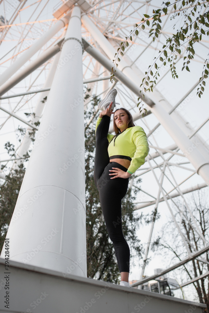 The girl acrobat in the park against the background of the Ferris wheel does stretching (yoga) The girl acrobat in the park against the background of the Ferris wheel does stretching (yoga)