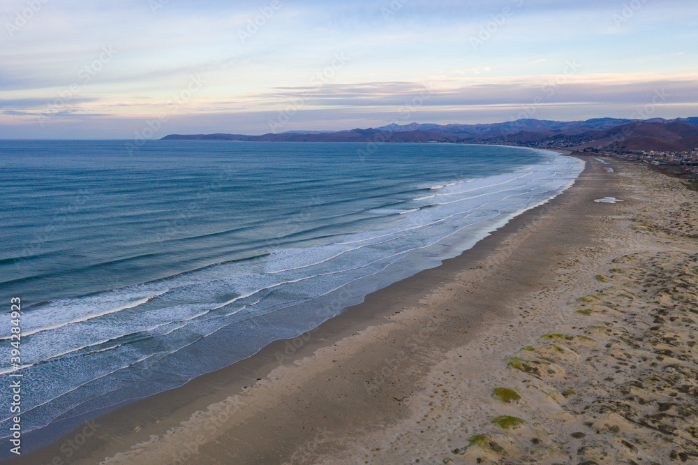 The Pacific Ocean washes onto a beach and sand dunes in Morro Bay, California. This coastal part of Central California is known for its beautiful and tranquil scenery. The Pacific Ocean washes onto a beach and sand dunes in Morro Bay, California. This coastal part of Central California is known for its beautiful and tranquil scenery.