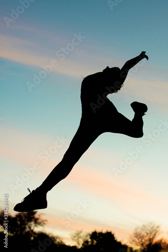 Girl acrobat at sunset doing stretching (yoga). Against the backdrop of beautiful clouds