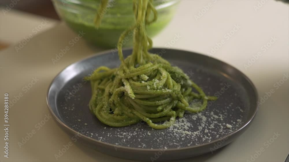 Man eating in a fine dining restaurant. The fork roll up some pesto spaghetti